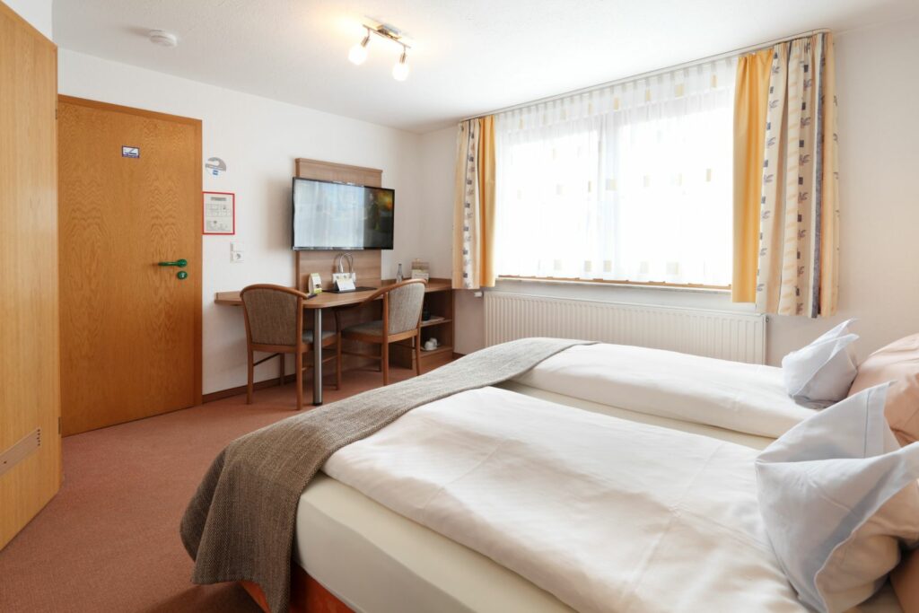 Komfortables Doppelzimmer mit zwei Betten, Schreibtisch, Fernseher und viel Tageslicht