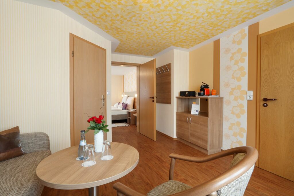 Eingangsbereich der Suite mit Sitzecke, Tisch, Kaffeemaschine und Blick ins Schlafzimmer