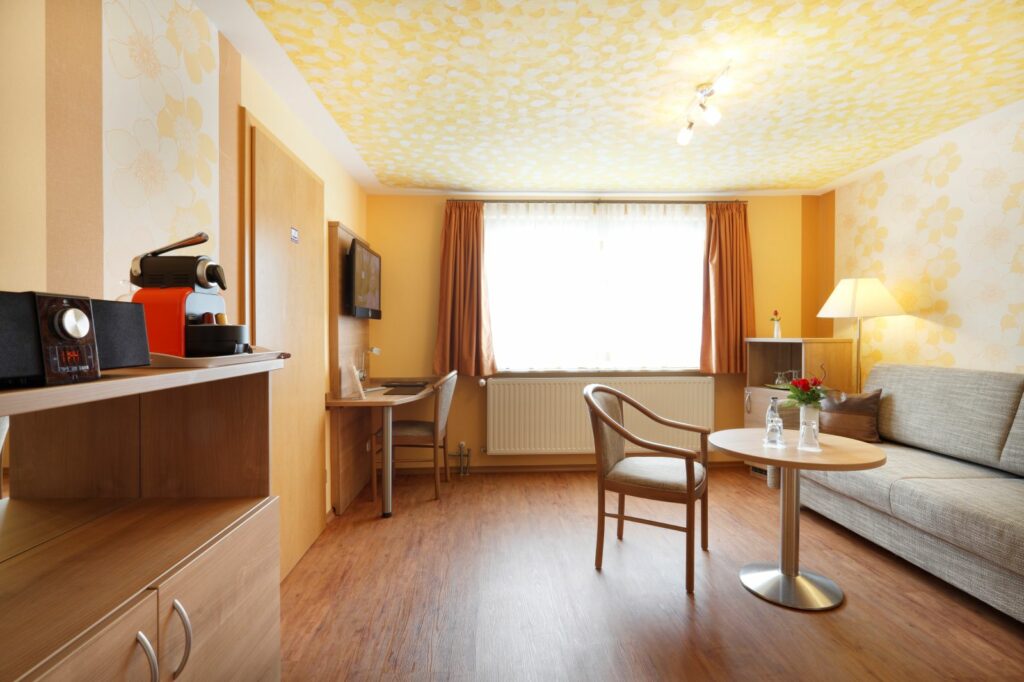 Geräumige Suite mit Sitzecke, Schreibtisch, Kaffeemaschine und warmem Farbkonzept