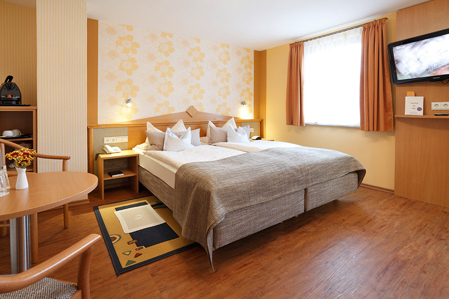 Superior Zimmer im Hotel Pension Stern mit Bett, Fenster und Sitzgruppe auf Holzboden