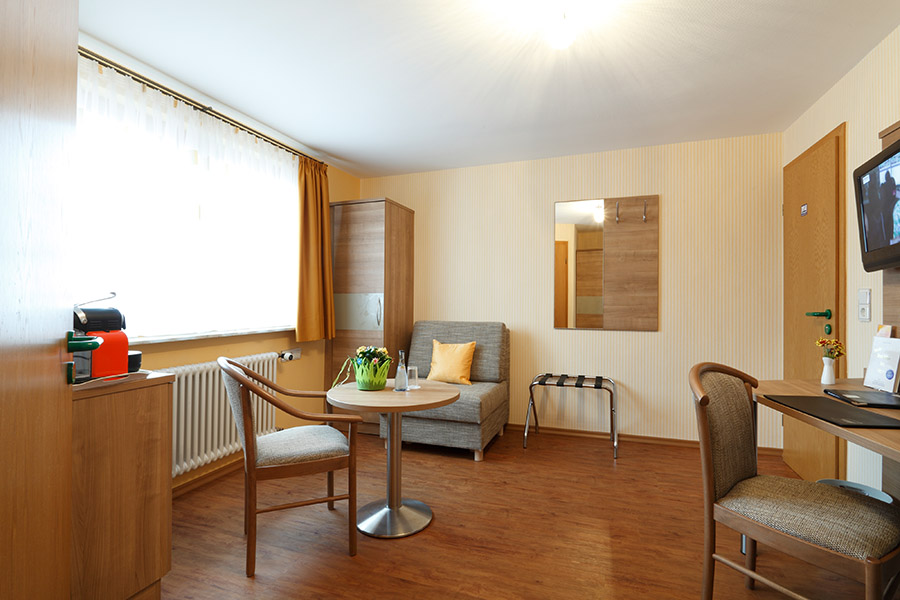 Sitzbereich im Superior Einzelzimmer des Hotel Pension Stern mit Tisch, Sesseln und Fenster